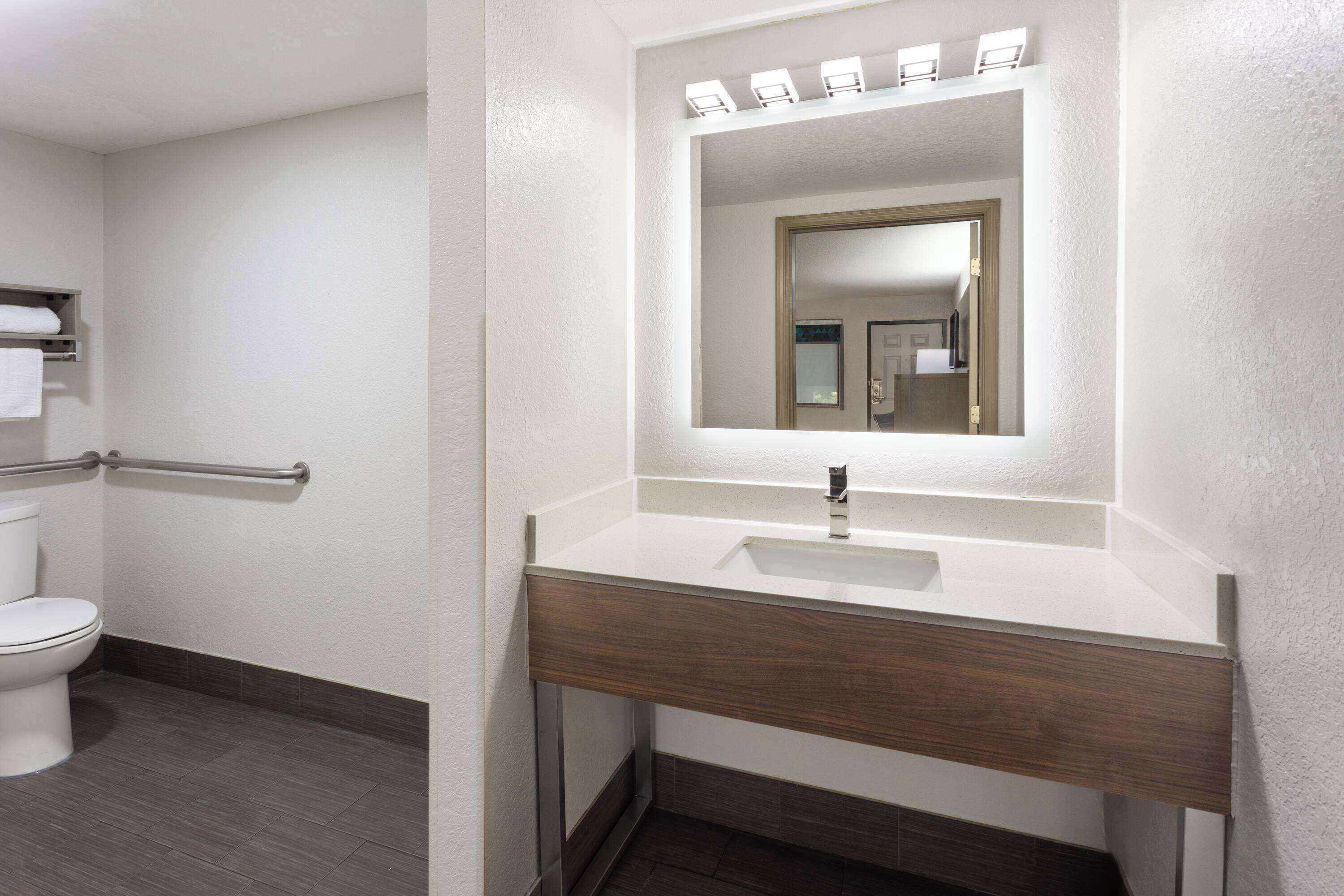 Une salle de bain avec un lavabo blanc, un miroir et des toilettes.