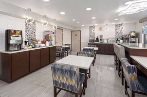 Um café moderno com balcão, área de estar e máquinas de café.