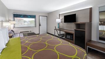 Hotelkamer met een groot bed, een flatscreen televisie aan de muur, een bureau met stoel en een raam met uitzicht op gebouwen.