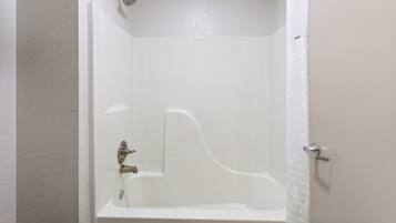 A white bathtub with a showerhead, a faucet, and a door handle.