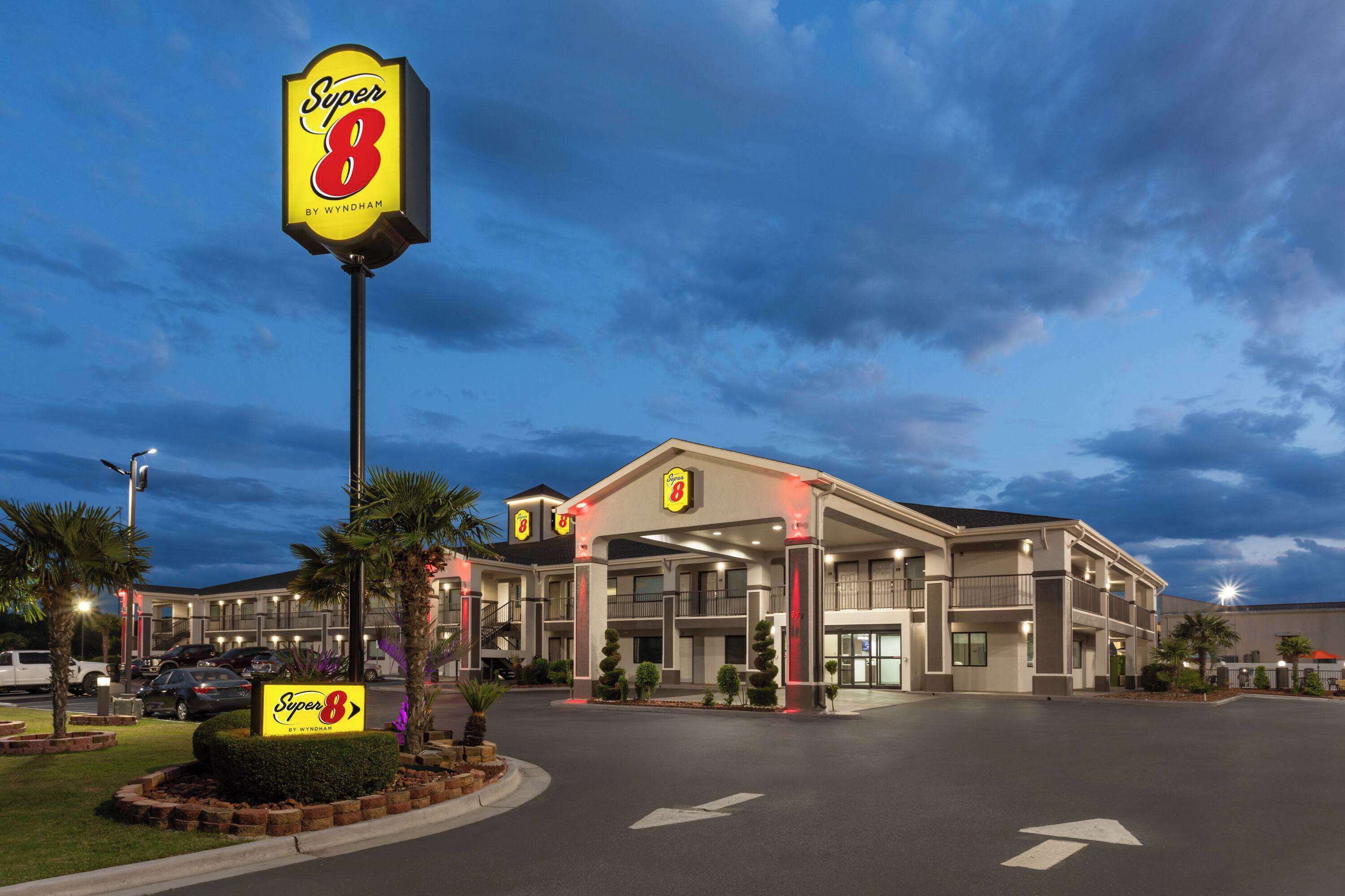 Un hotel Super 8 con un letrero grande, varios balcones y un estacionamiento.