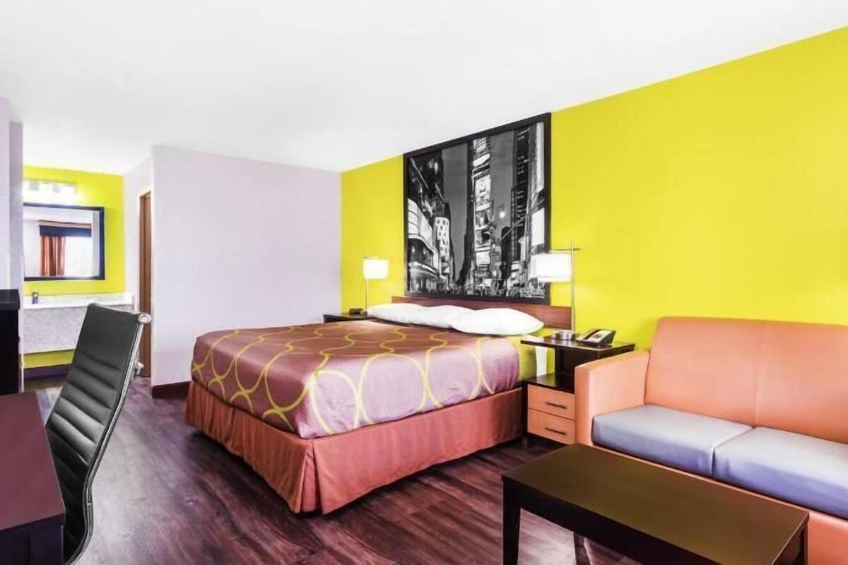 A hotel room with a bed, a sofa, a desk, and a nightstand.
