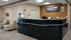 A reception desk with a black marble top, beige chairs, a framed picture on the wall, and a "No Pets in Hotel" sign.