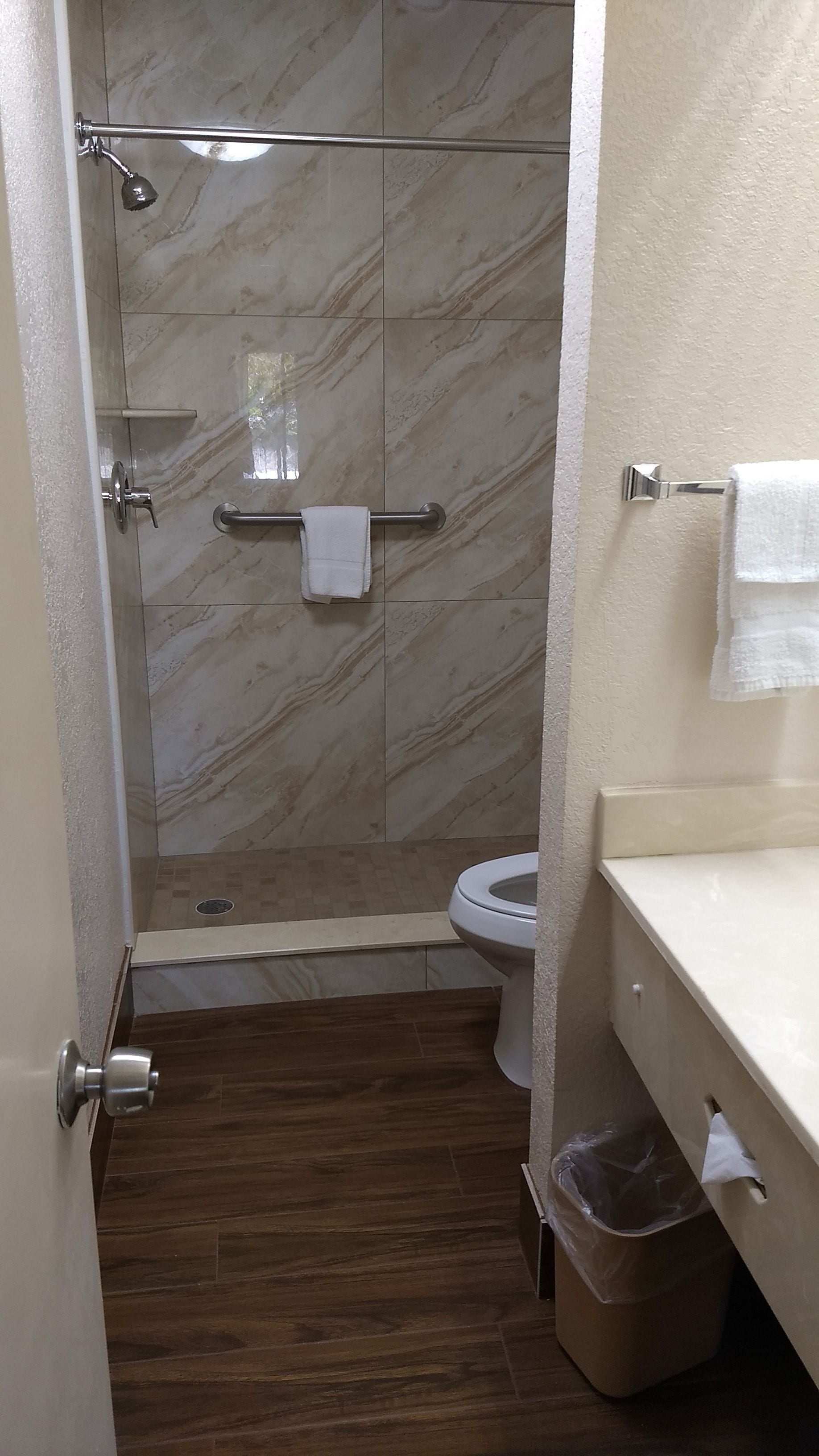 A bathroom with a shower, toilet, and a towel rack.