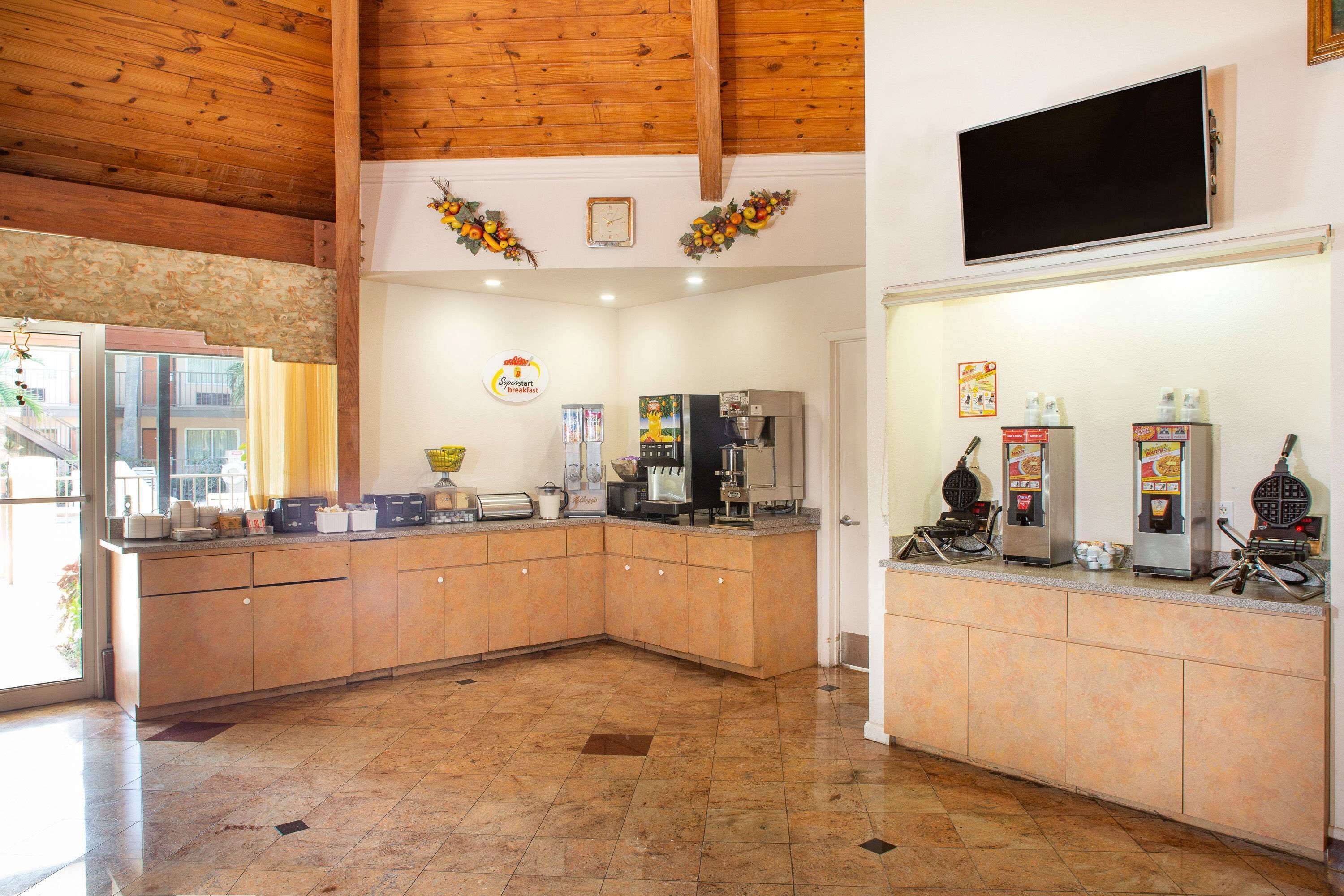 A kitchen with a wooden ceiling, a flat-screen TV, and a coffee machine.