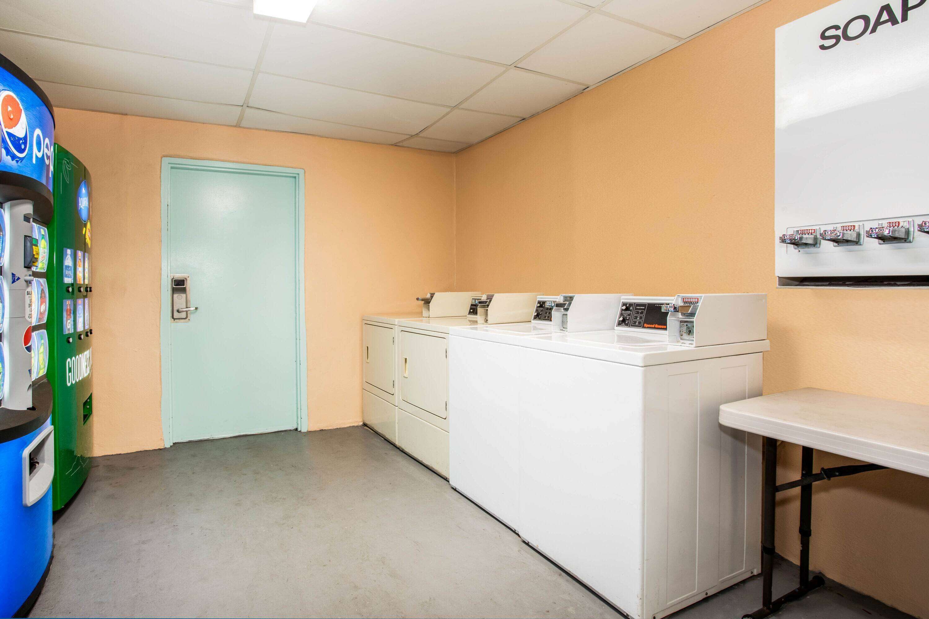Une buanderie équipée d’un lave-linge, d’un sèche-linge et d’un distributeur de savon fixé au mur.