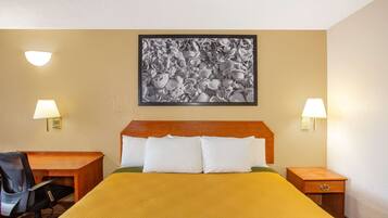 Habitación de hotel con cama, escritorio, dos sillas y dos mesitas de noche con lámparas.