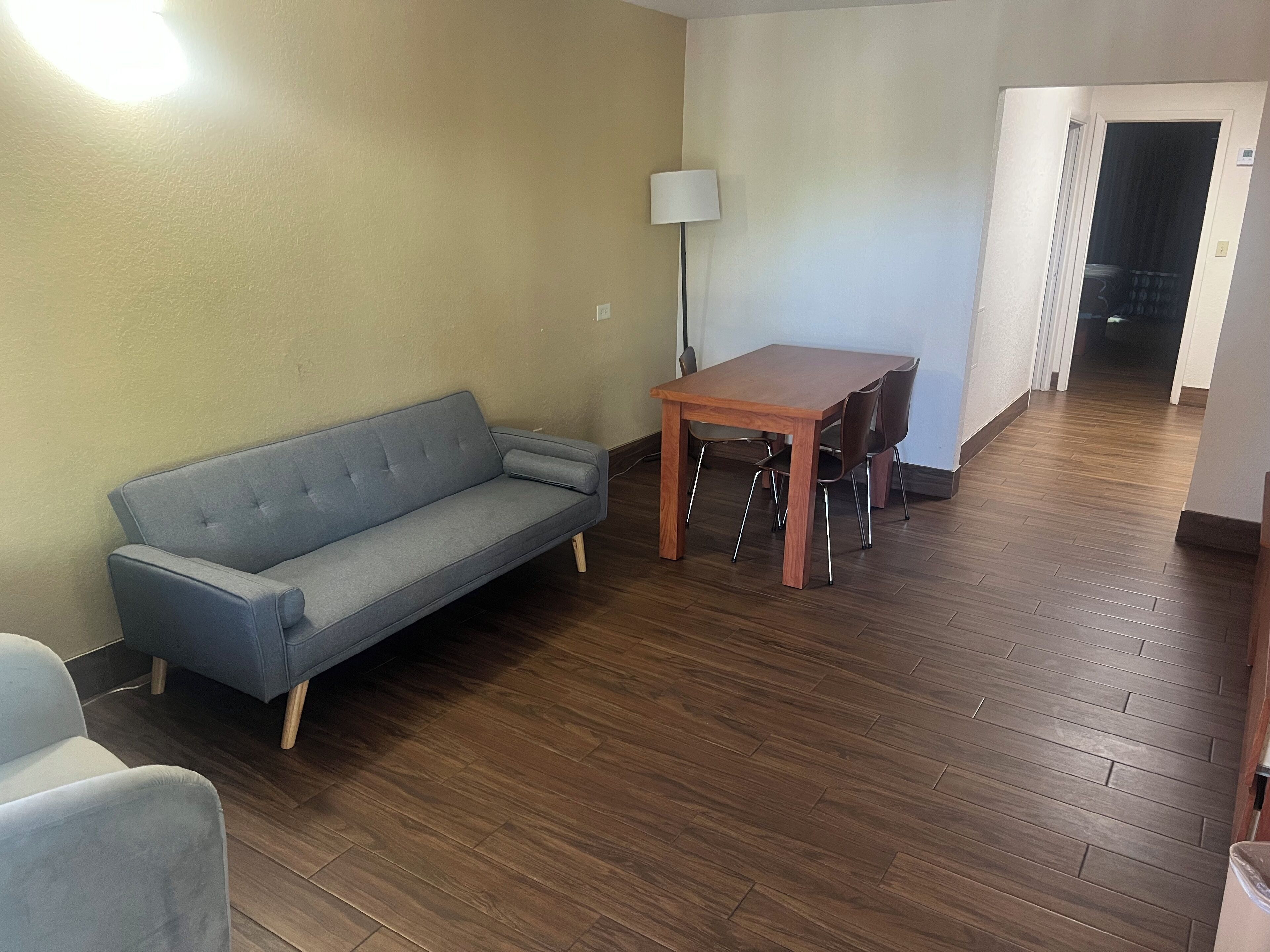 Uma sala de estar com sofá, mesa de jantar de madeira e cadeiras.