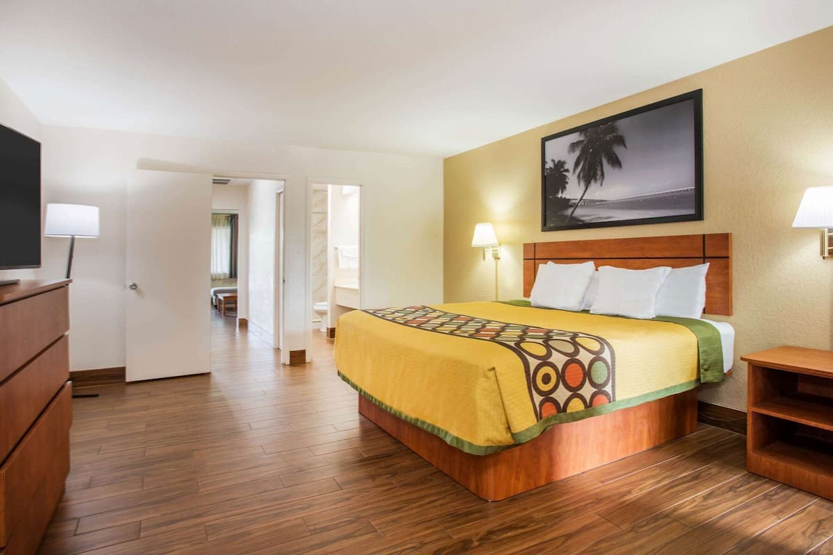 A hotel room with a bed, a television, a desk, and a painting on the wall.