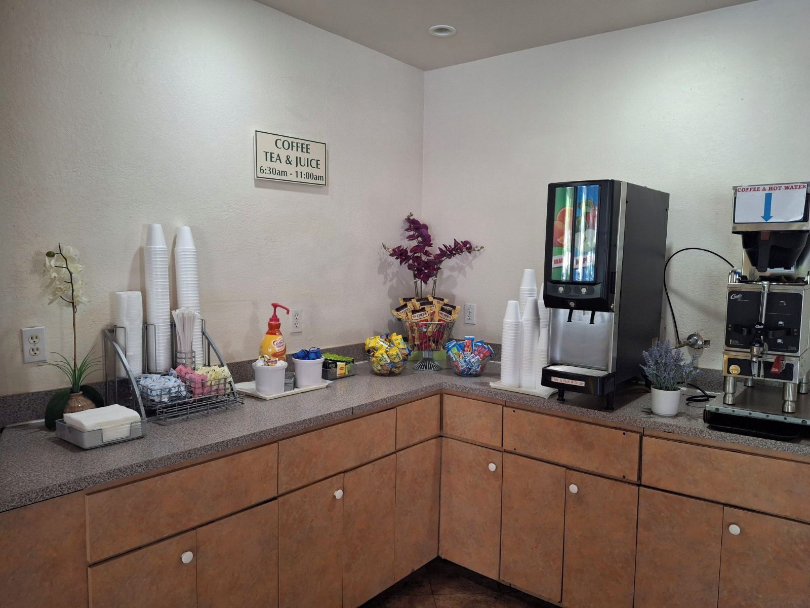A coffee station with a coffee machine, cups, and condiments.