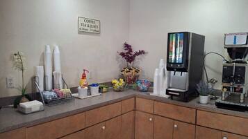 Una estación de café con cafetera, tazas y complementos.