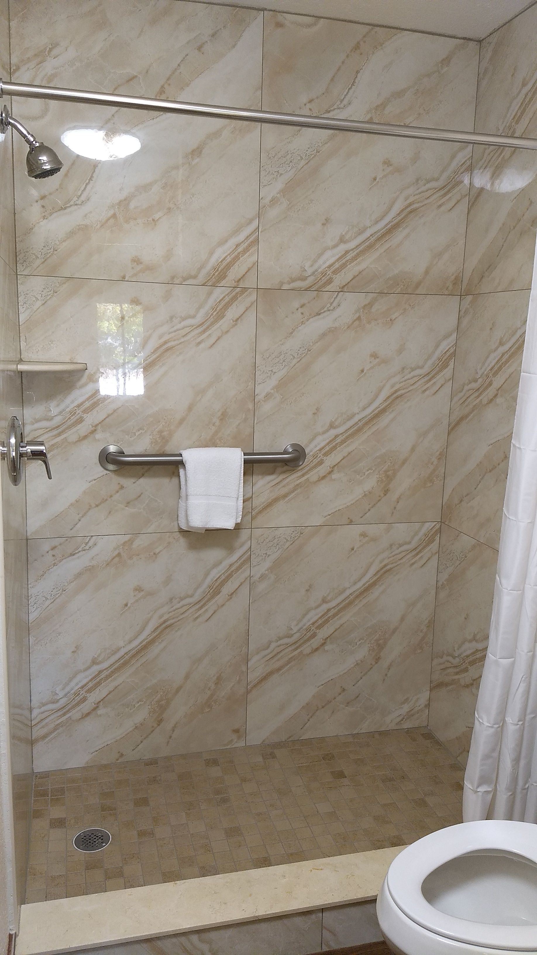 Un baño con ducha, inodoro y toallero.
