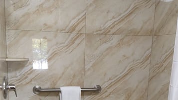 Un baño con ducha, inodoro y toallero.