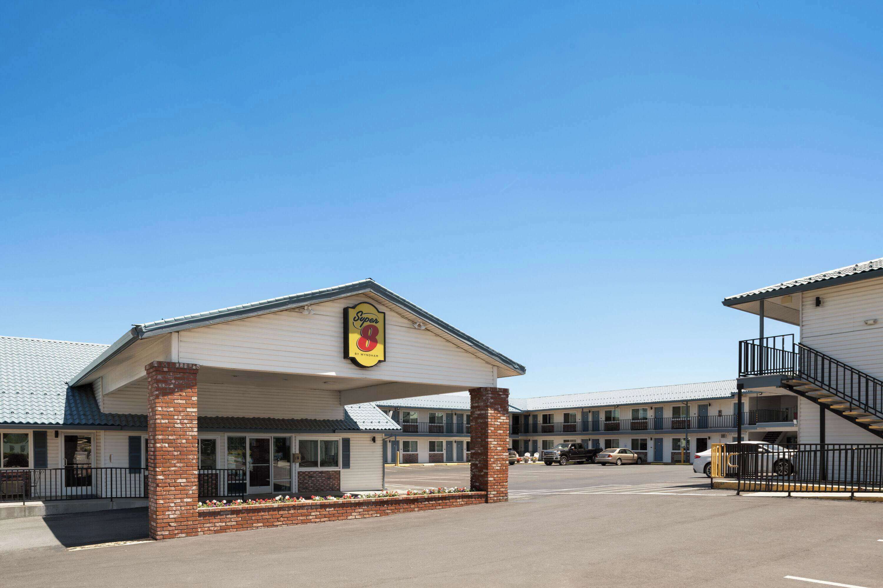 A motel with a covered entrance, a brick pillar, and a staircase leading to an upper level.