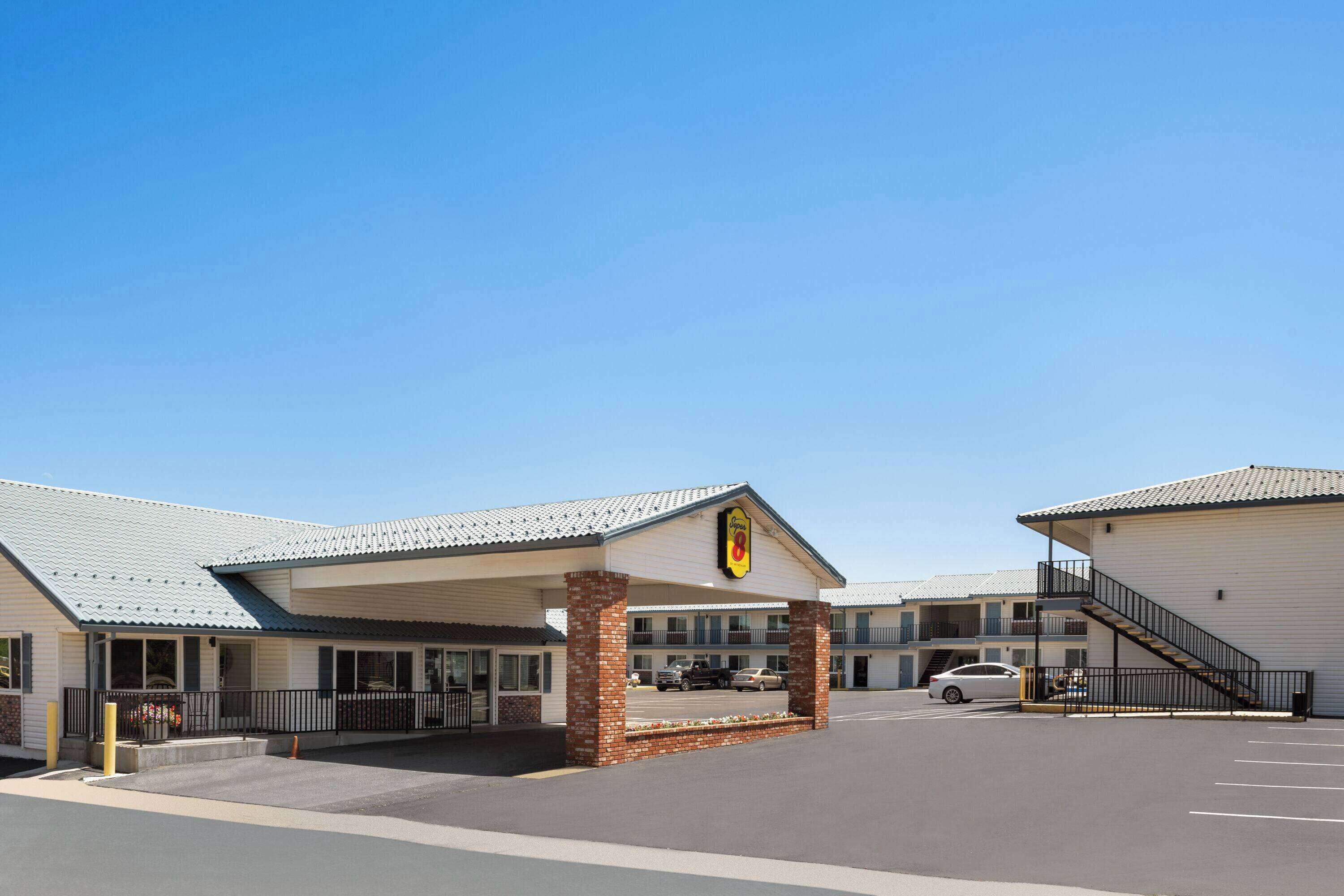 Un motel doté d’une entrée couverte, d’un parking et d’un escalier menant à un étage supérieur.