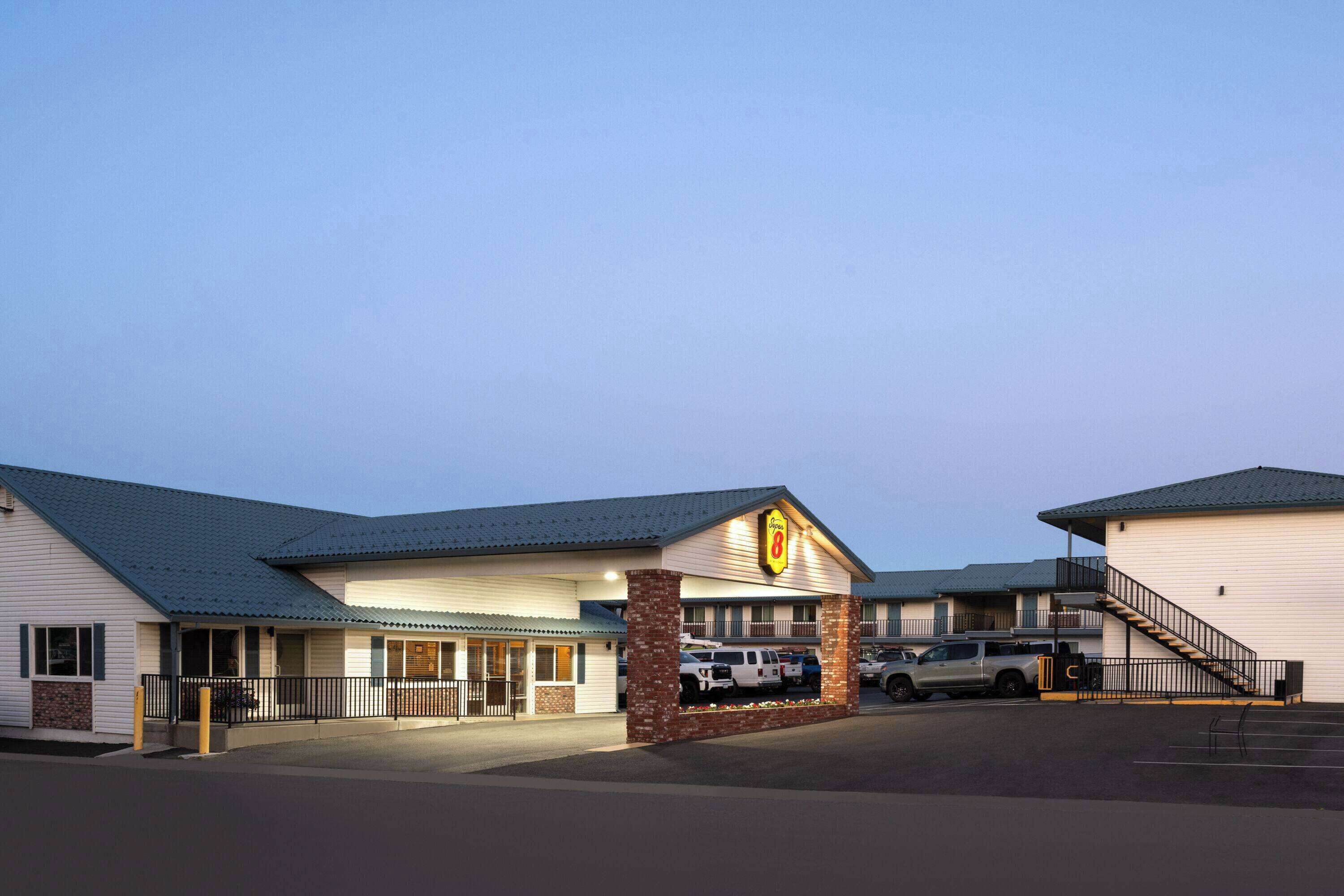 A motel with a prominent '8' sign, a covered parking area, and a staircase leading to the entrance.