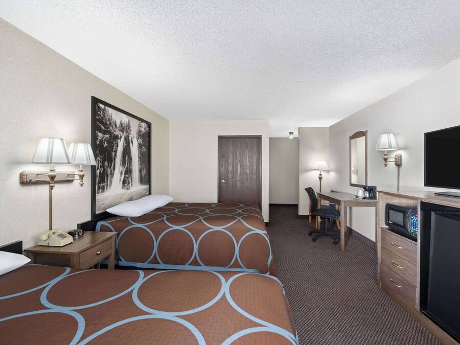 A hotel room with two beds, a desk, a television, and a microwave.