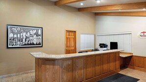Un espace d’accueil avec un comptoir en bois, un panneau encadré représentant la Californie, une porte et une fenêtre avec des stores.