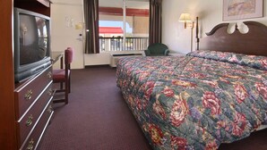 Une chambre d’hôtel avec un grand lit, une télévision, une chaise et une fenêtre avec des rideaux.