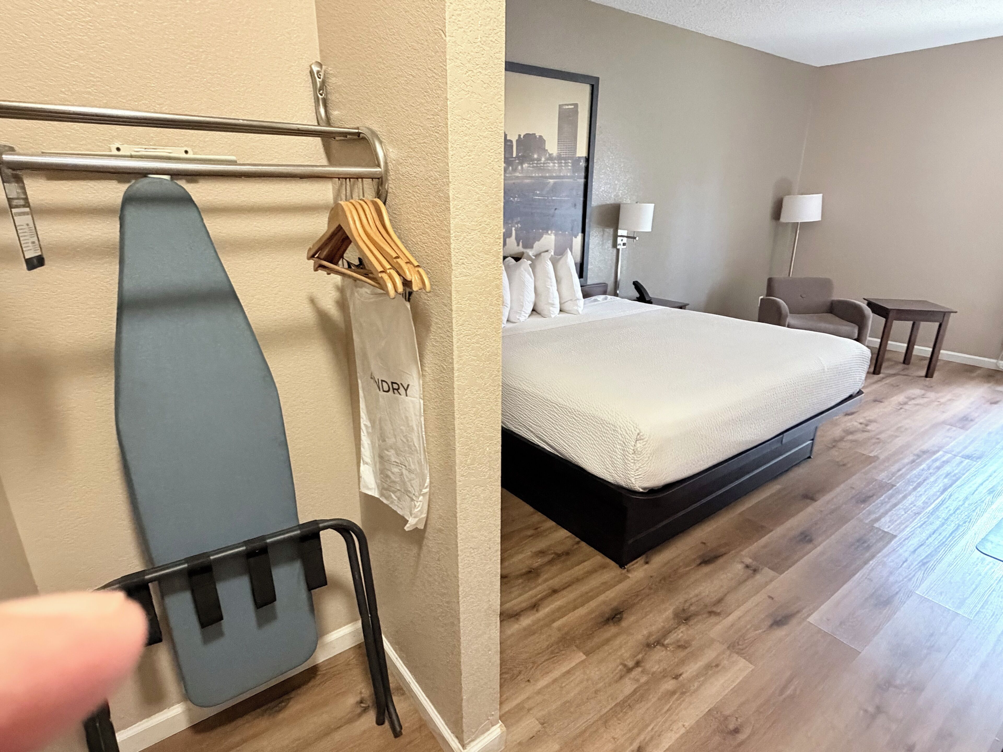 A hotel room with a bed, a chair, a desk, and a cityscape view.