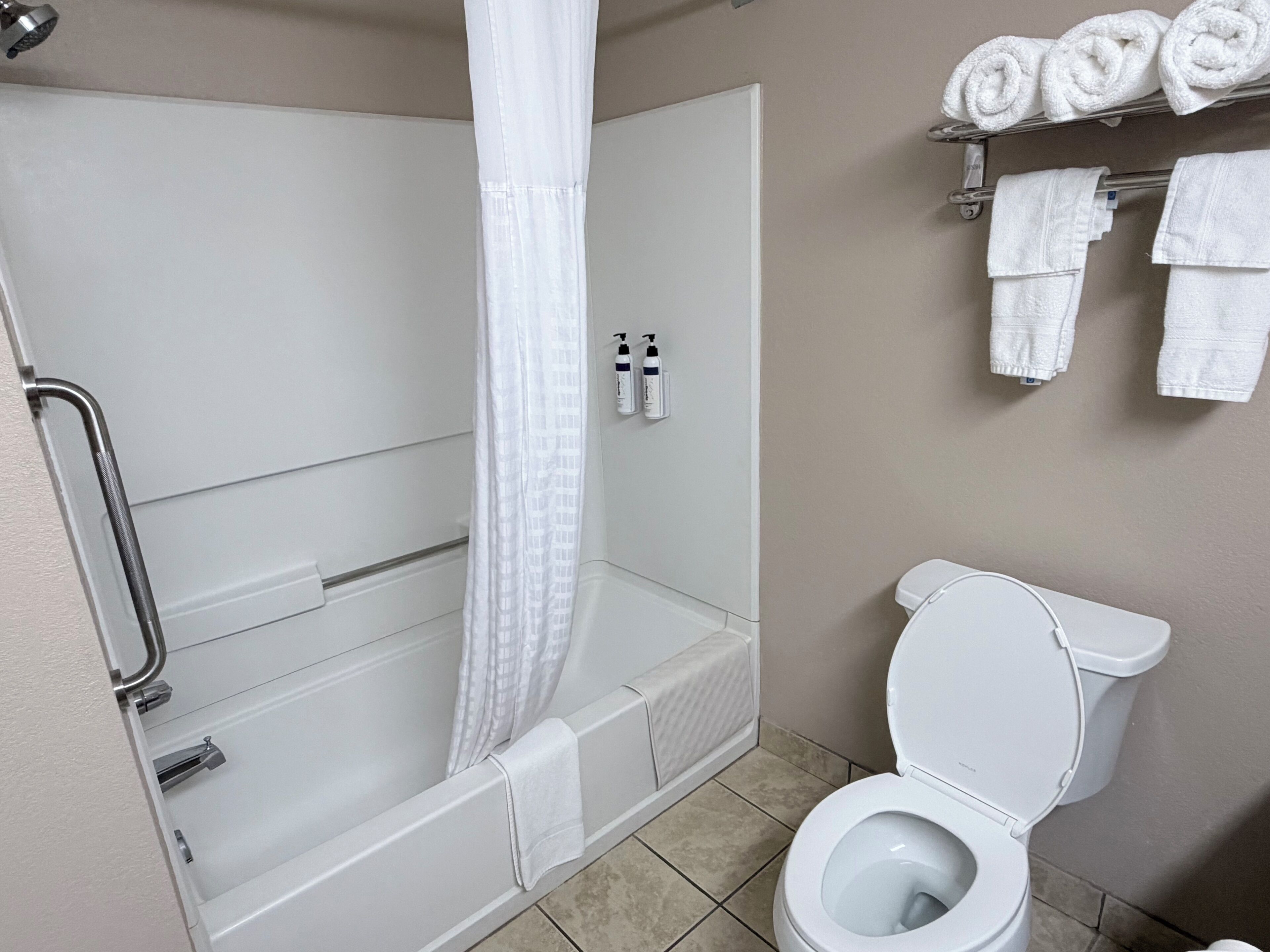 Un baño con bañera, inodoro y cortina de ducha.
