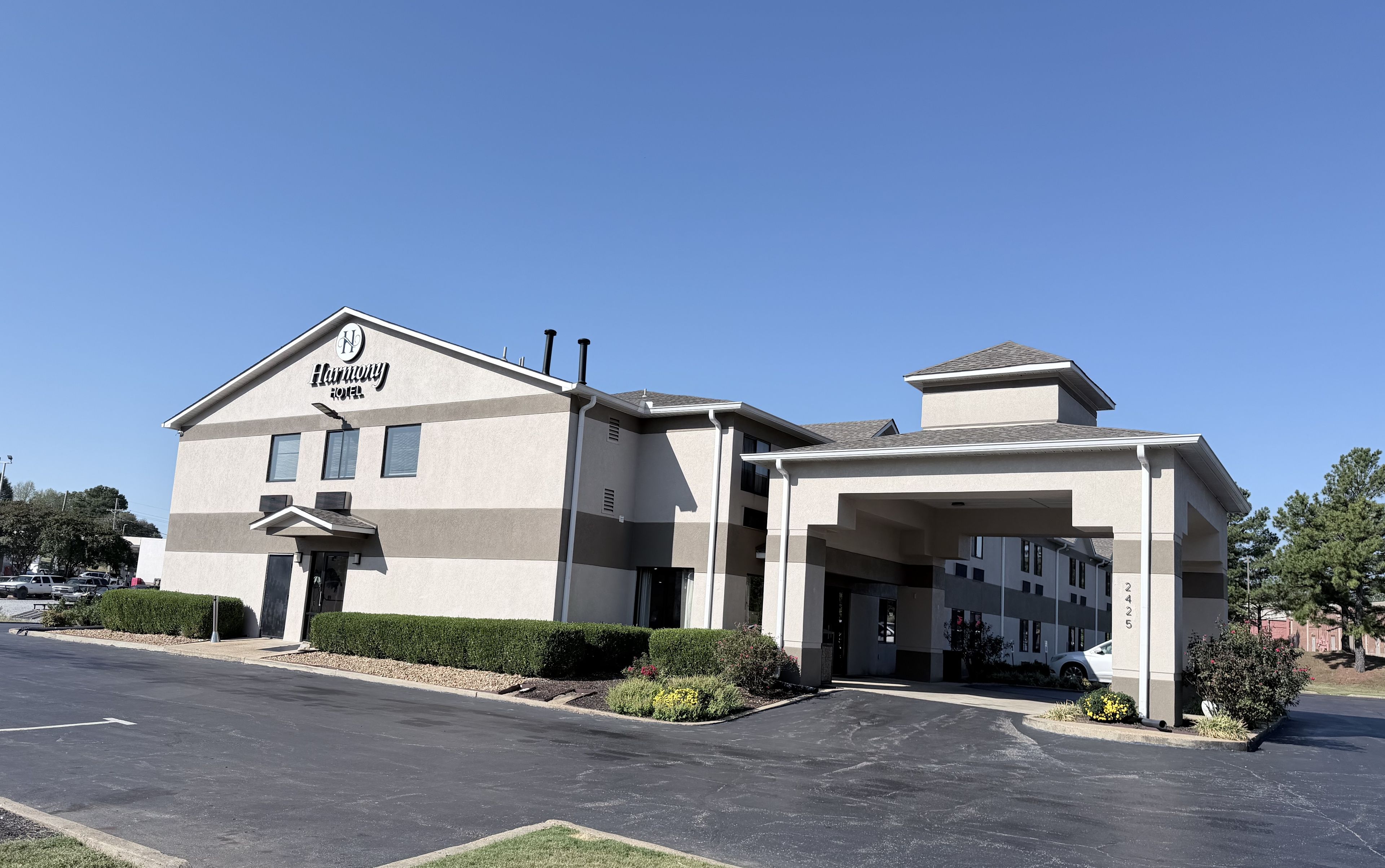A Harmony Hotel with a modern design, featuring a prominent entrance and a parking lot.
