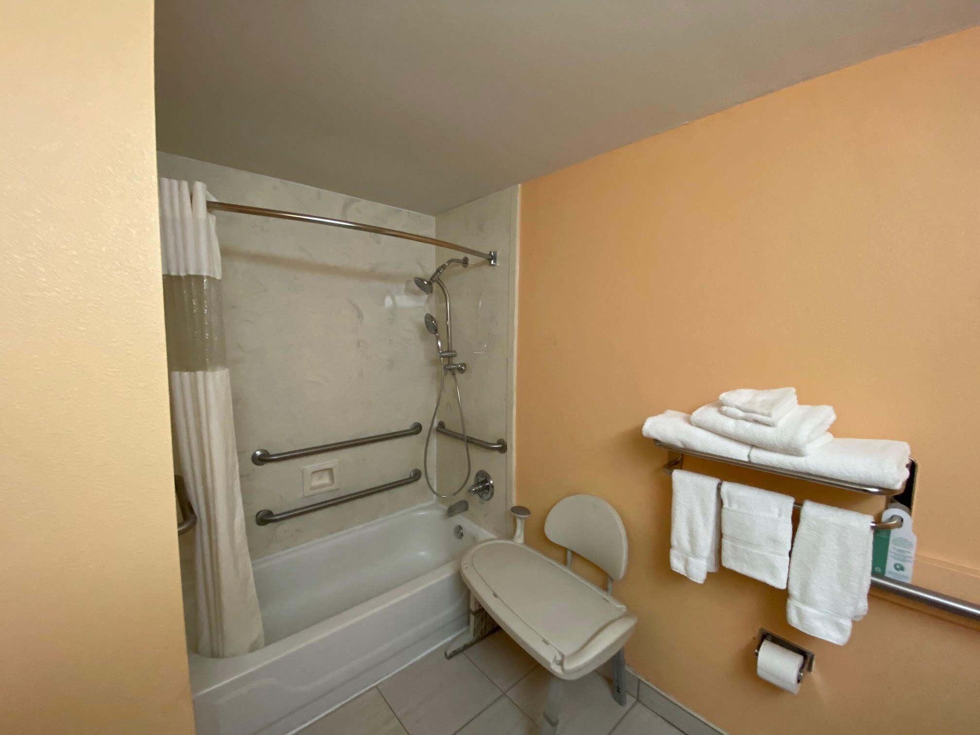 A bathroom with a bathtub, a shower, a toilet, and a towel rack with towels.