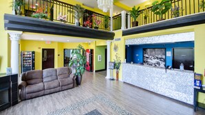 A hotel lobby with a reception desk, a sofa, and a staircase.