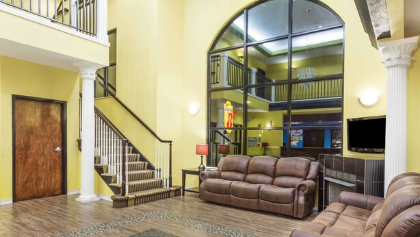 A spacious living area with a large window, a staircase, and leather sofas.