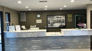 Un mostrador de recepción con fachada de piedra, un reloj y un cartel que dice 'Greetings from Illinois'.