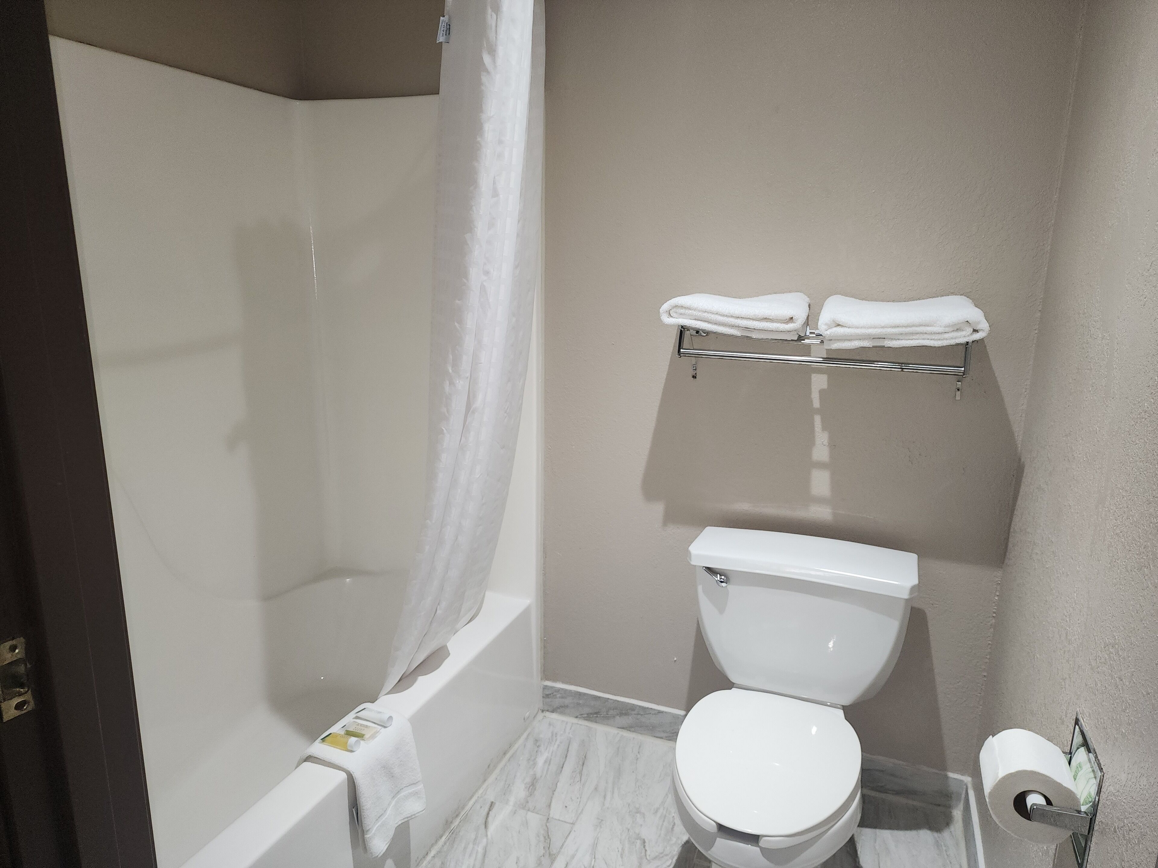 A bathroom with a bathtub, toilet, and a towel rack.