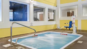 Una pequeña piscina interior con una escalera metálica, decoración azul y blanca y un letrero que indica una capacidad para 12 personas.