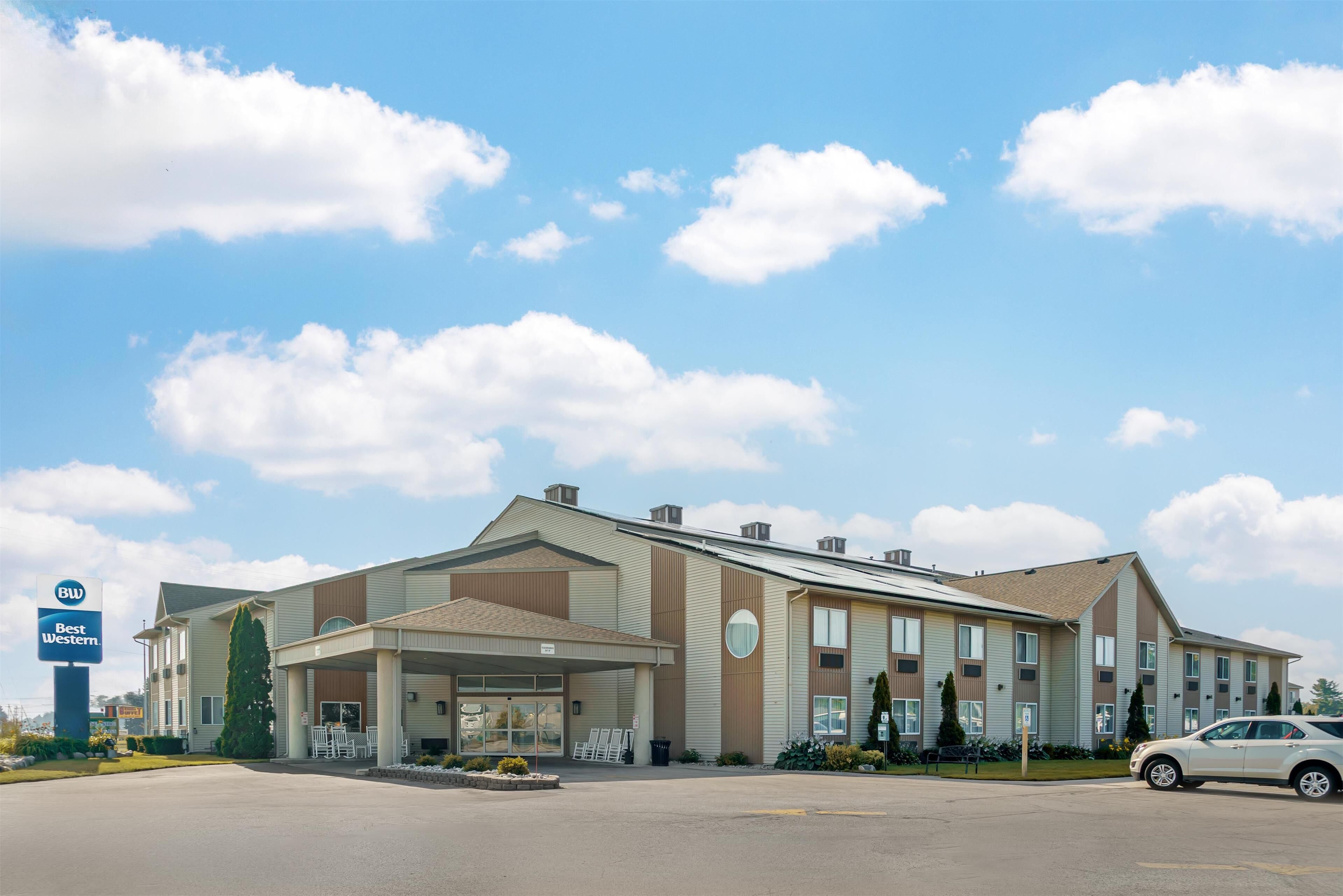 A hotel with a covered entrance, a parking lot, and a Best Western sign.
