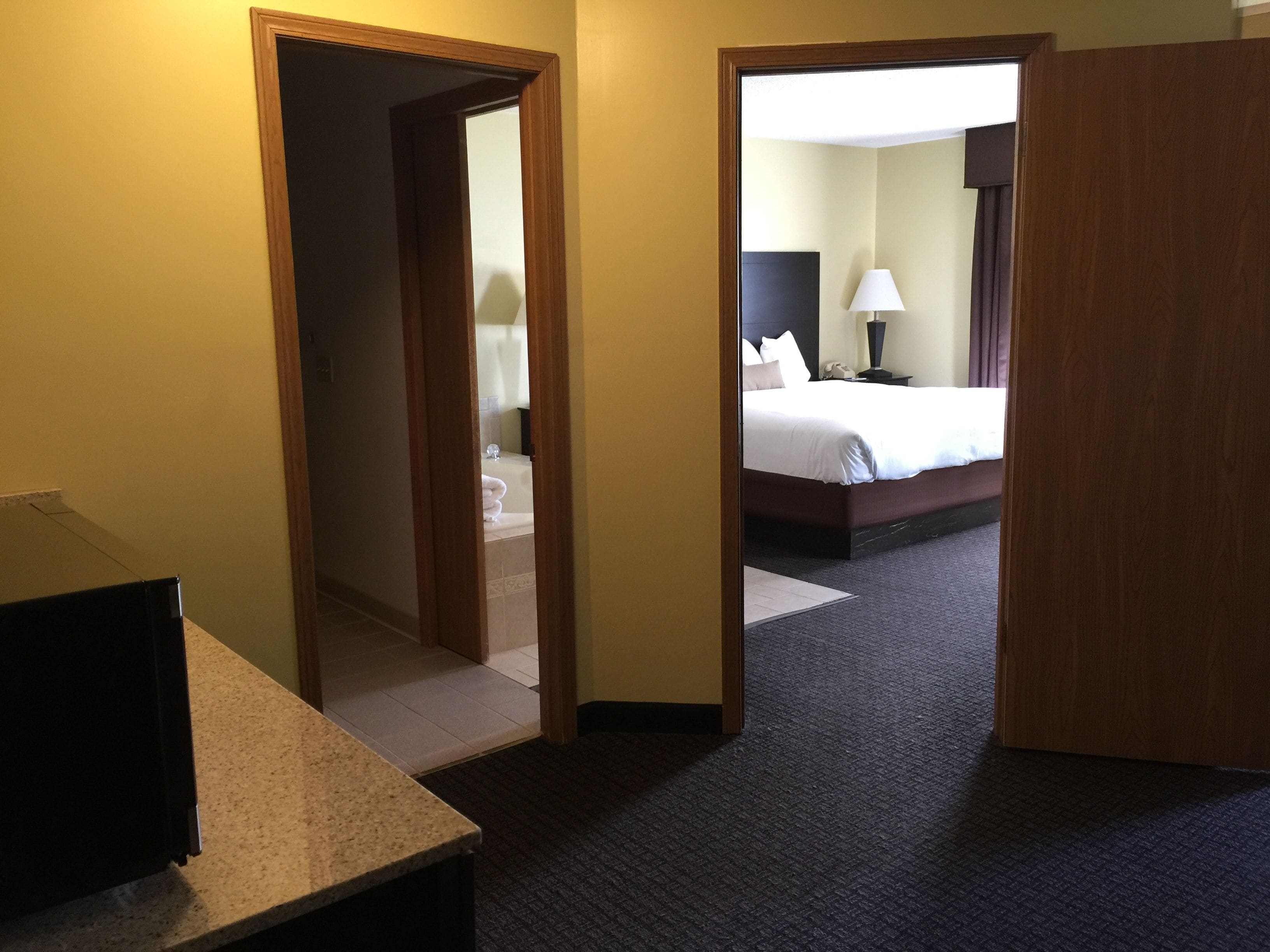 Una habitación de hotel con cama, escritorio y baño visible a través de una puerta abierta.