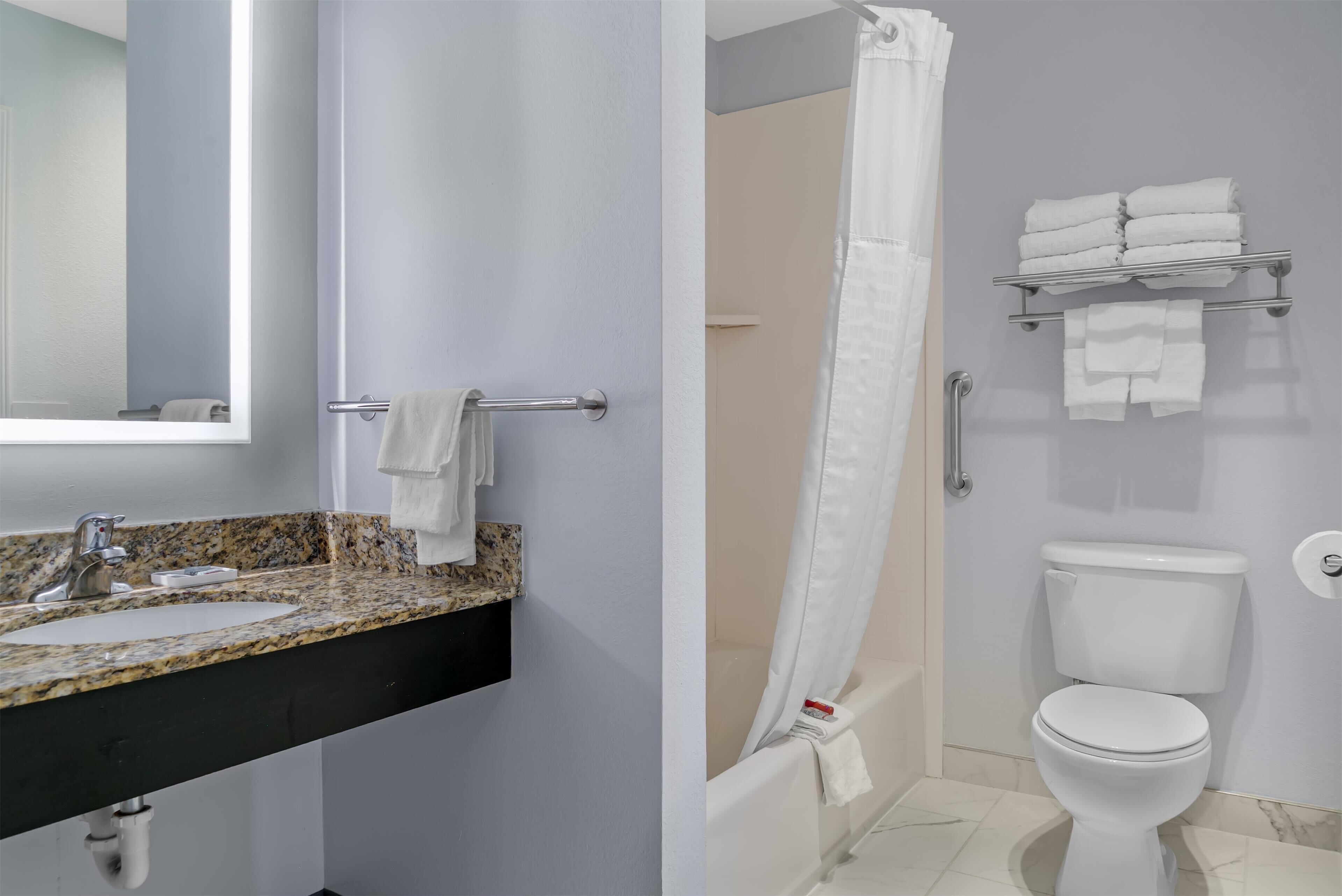 A bathroom with a granite countertop sink, a towel rack, a toilet, and a shower curtain.