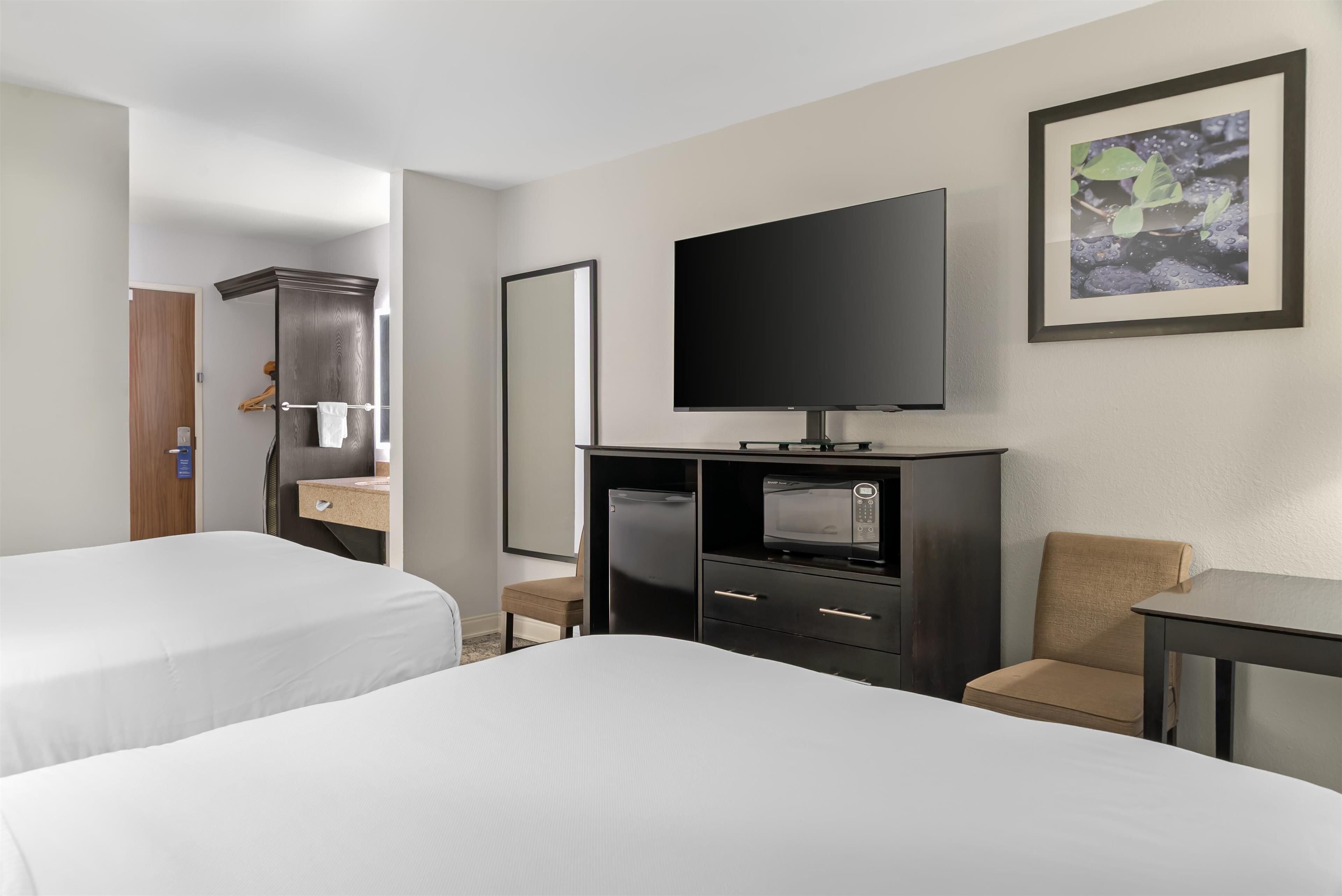 Een hotelkamer met twee bedden, een televisie, een bureau en een stoel.