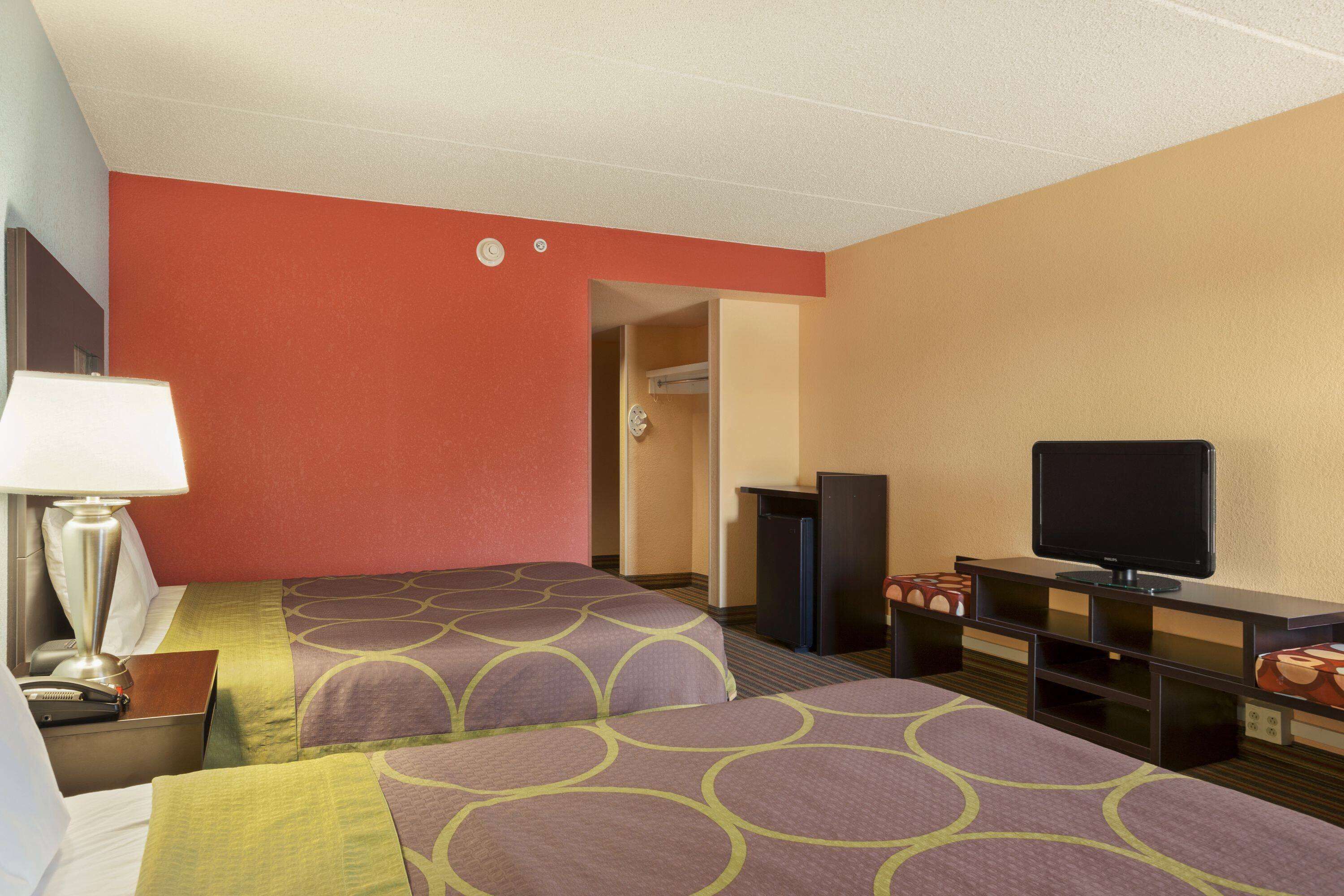 Une chambre d’hôtel avec deux lits, une télévision, un bureau et une lampe.