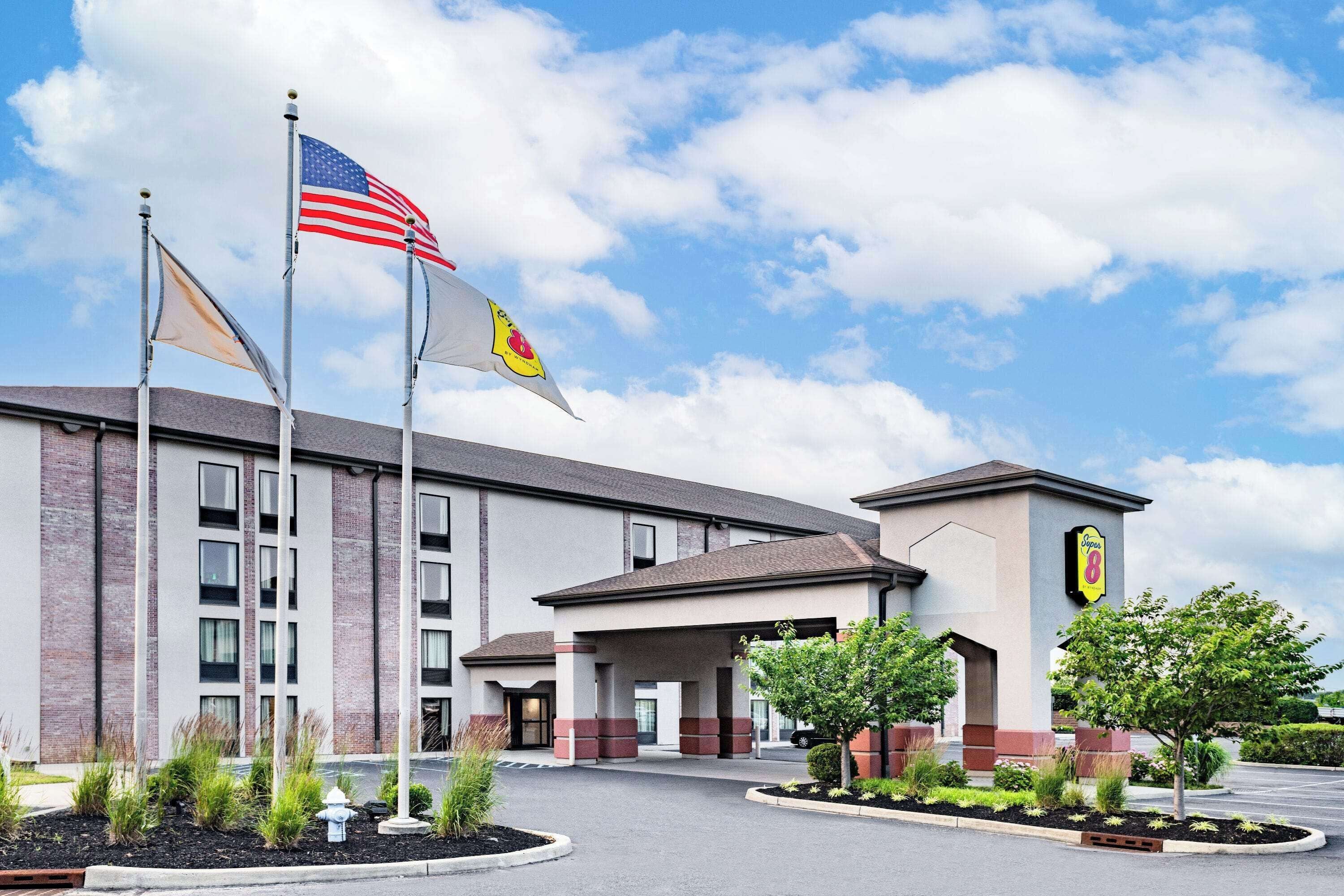 Um hotel com fachada de tijolos, bandeiras americanas e placa indicando Hampton Inn.