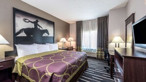 Habitación de hotel con una cama grande, dos lámparas de noche, un escritorio con silla, televisor y un ventanal con cortinas.