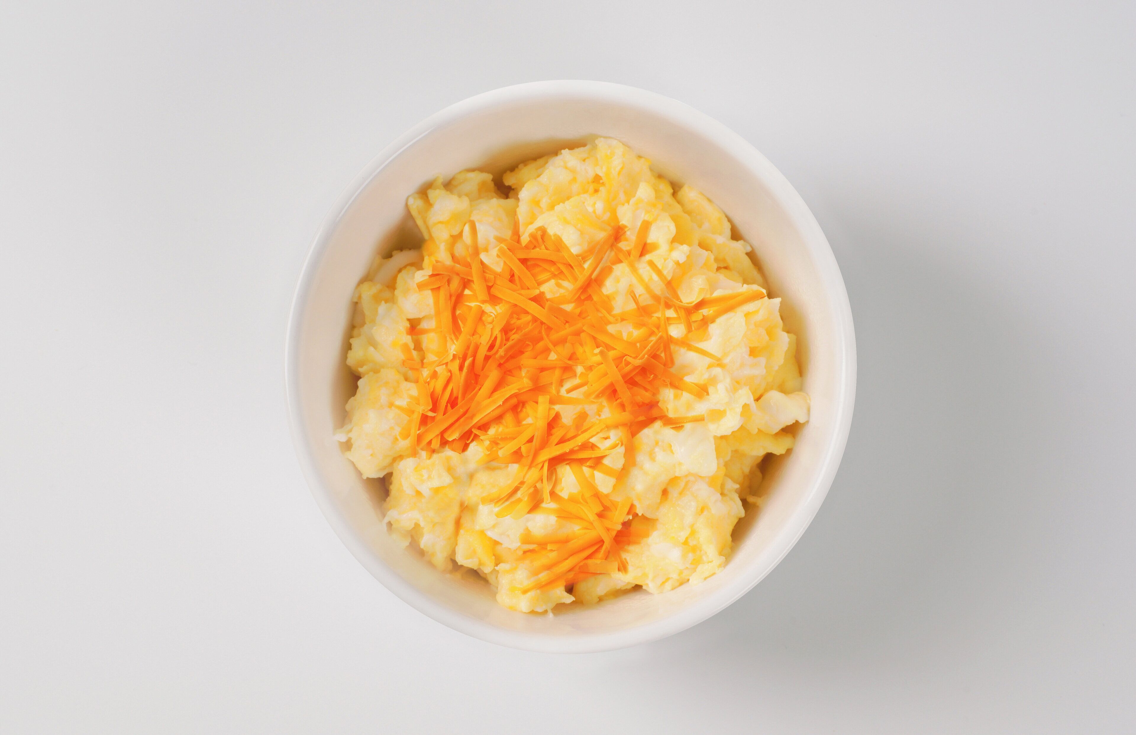 A bowl of mashed potatoes topped with shredded carrots.