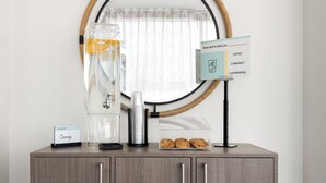 Une petite cuisine équipée d’une machine à café, d’une carafe en verre et d’un panneau indiquant que du jus d’orange est disponible.