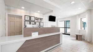 Un comptoir d’accueil d’hôtel au design moderne, agrémenté d’œuvres d’art encadrées au mur et surmonté d’un téléviseur à écran plat.