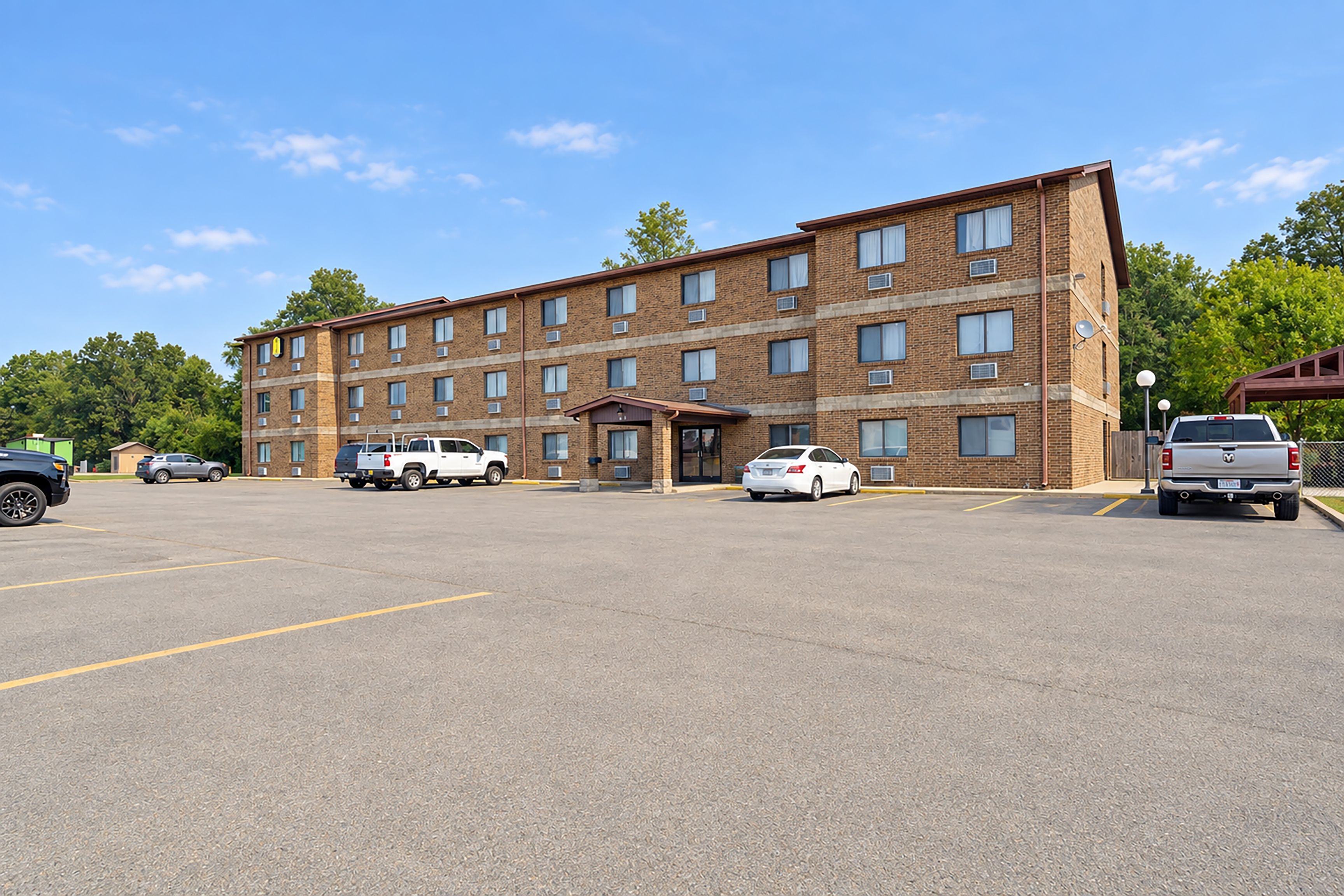 A multi-story brick building with a parking lot in front.