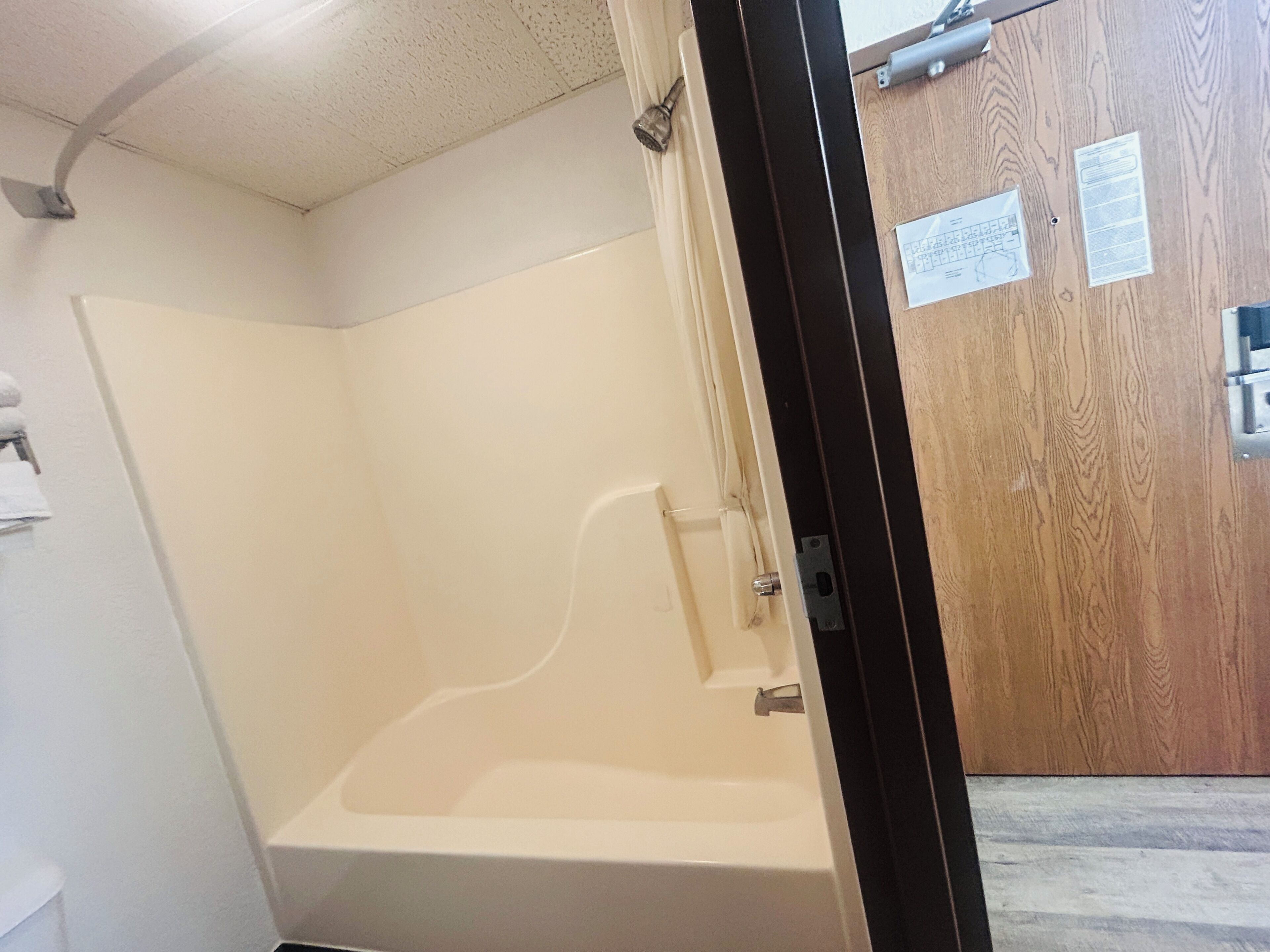 A bathroom with a bathtub, a wooden door, and a white ceiling.
