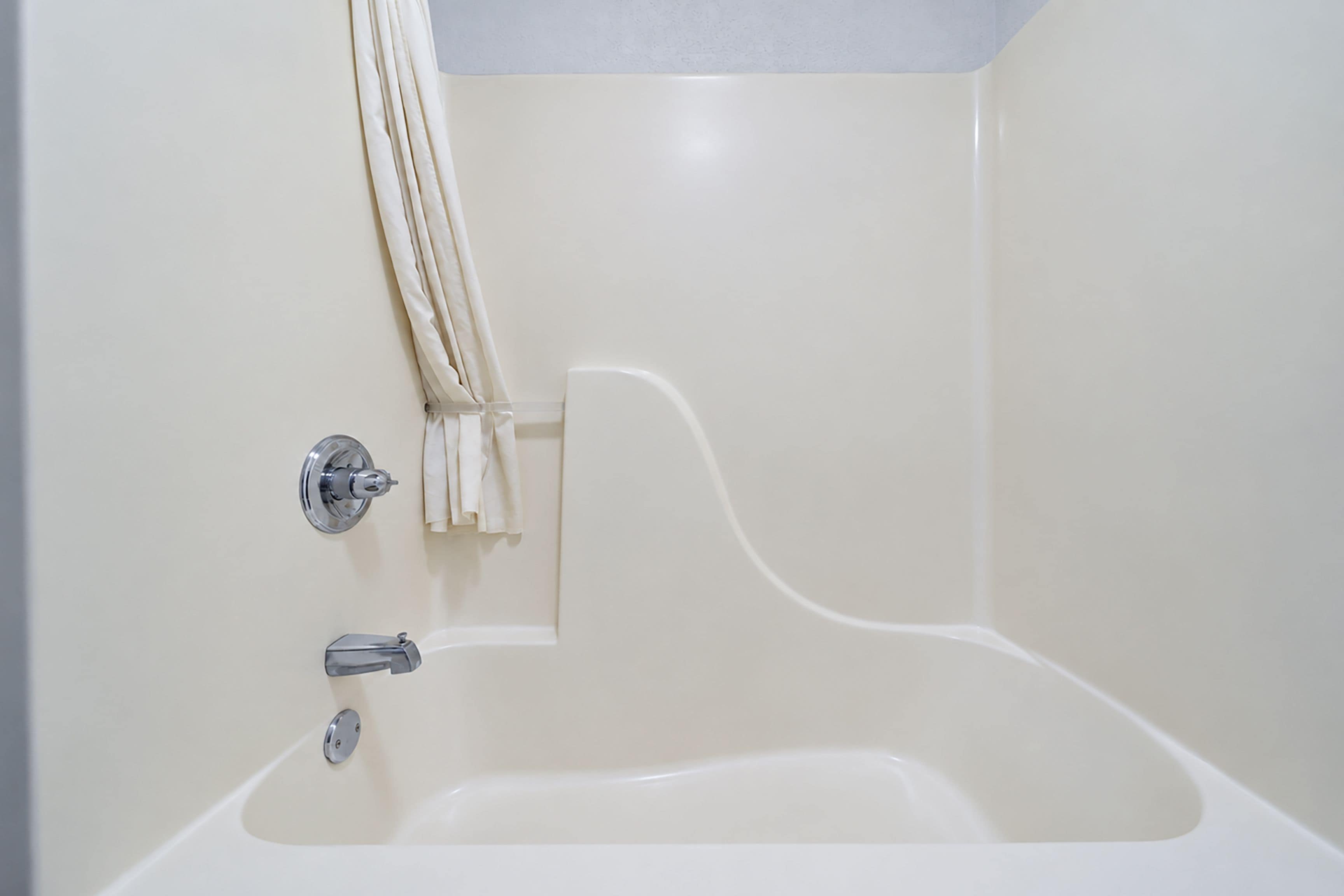 A bathtub with a chrome faucet and a wall-mounted towel rack with towels.