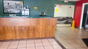 A reception desk with a framed welcome sign, a fire extinguisher, and a caution sign on the floor.