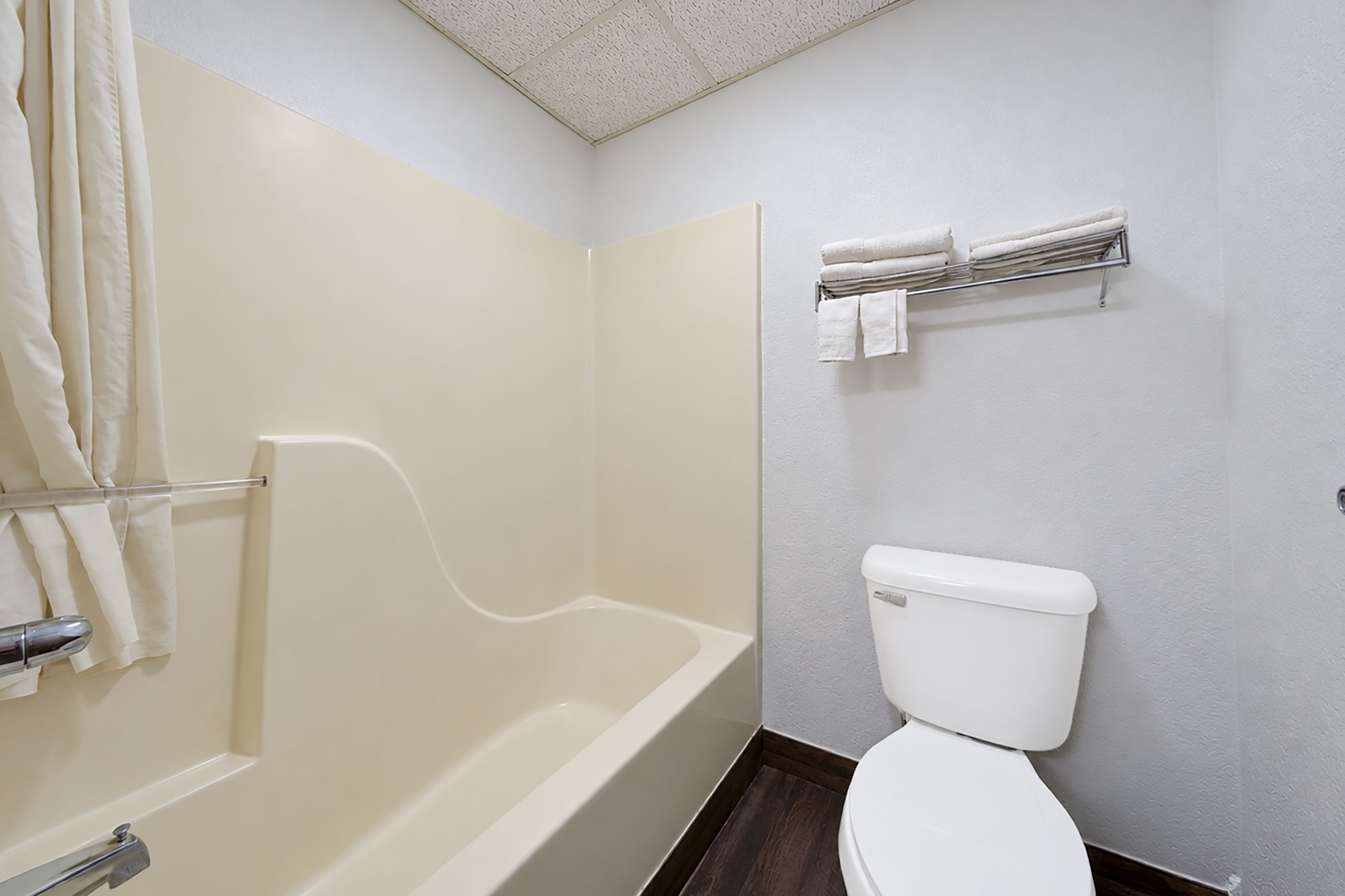 A bathroom with a bathtub, toilet, and towel rack.