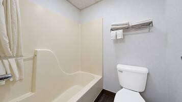 A bathroom with a bathtub, toilet, and towel rack.