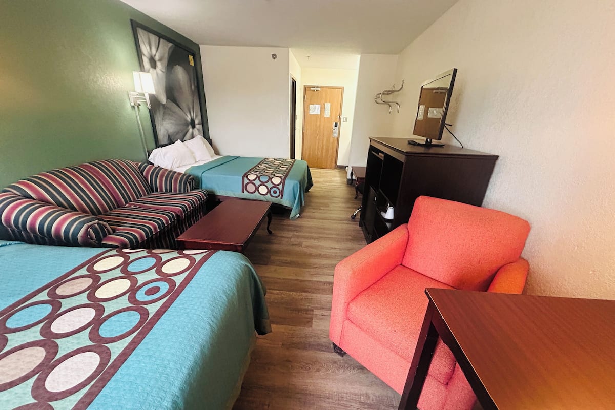 A hotel room with two beds, a desk, a chair, and a mirror.