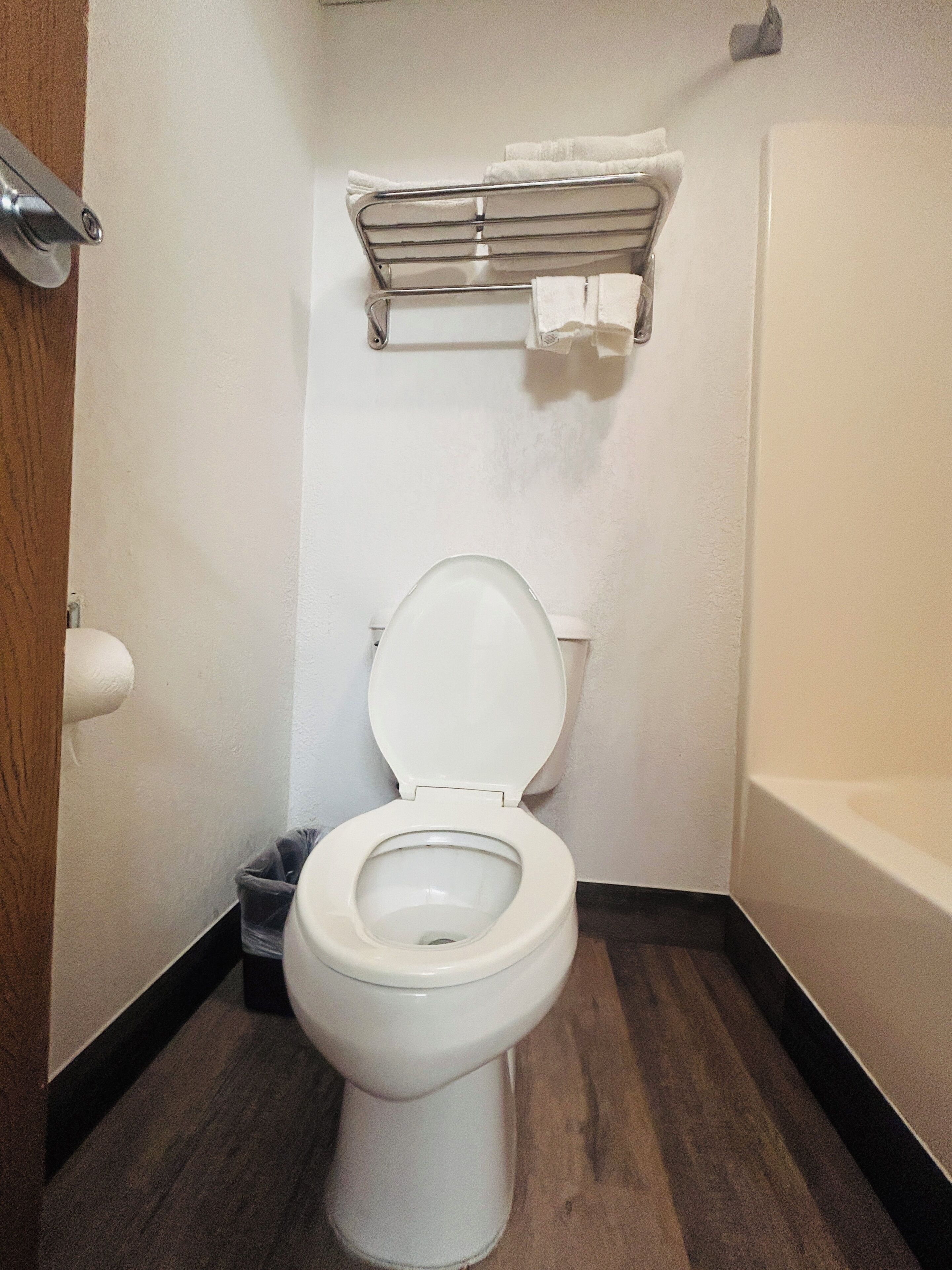 A bathroom with a toilet, a towel rack, and a shower area.